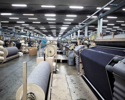 Weaving fabric on air jet looms in big textile weaving unit.